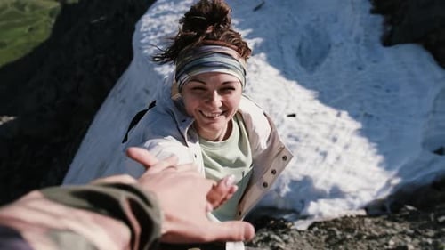 Mature Woman on a Hikinig Adventure Holding Man's Hand Helping Her Climb on Mountain Hill