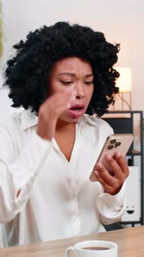 Woman Looks Worried While Using Mobile Phone Indoors