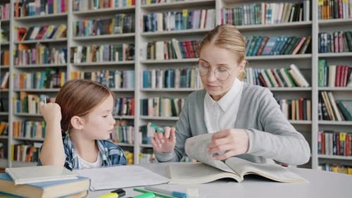 Young Teacher Helps Little Schoolgirl Perform Homework Task