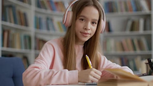 Teen Girl Studying with Headphones in Library