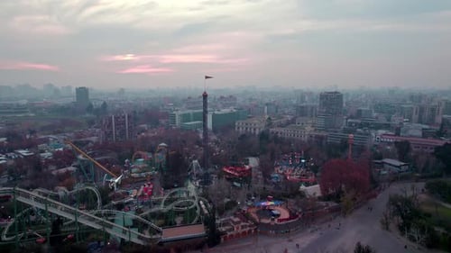 Aerial parallax revealing O'Higgins theme park in middle of cityscape at sunrise in Santiago de