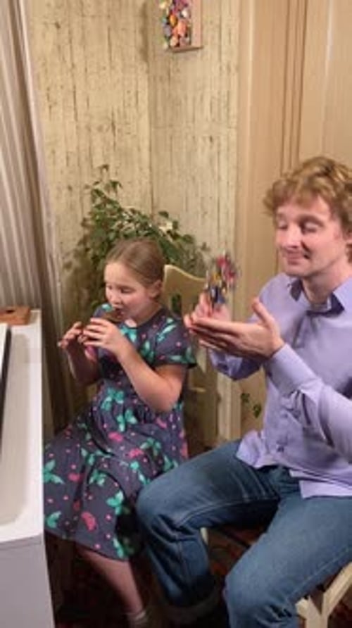 Young Girl Plays Woodwind Instrument with Encouragement