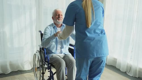 Rehabilitation Healthcare Physiotherapist Nurse Helps Old Man Patient in Wheelchair Stand Up Walking