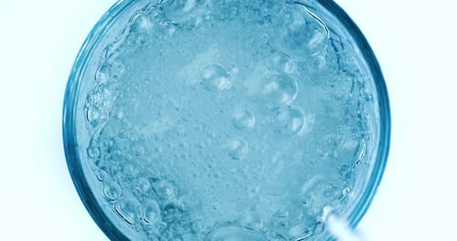 Pouring fresh pure sparkling water from bottle into a glass. Bubbles in water on super slow motion.