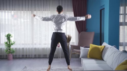 Junger fitter Mann macht zu Hause Springübungen.