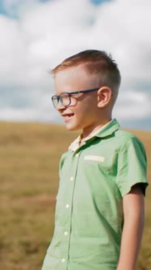 Garçon souriant dans des lunettes profitant du soleil en pleine campagne