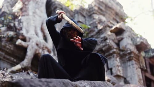 Mysterious Masked Warrior Poses With Sword on Ruins
