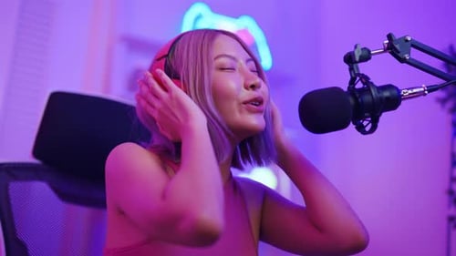 Asian young audio DJ woman dance with music and broadcasting in studio.