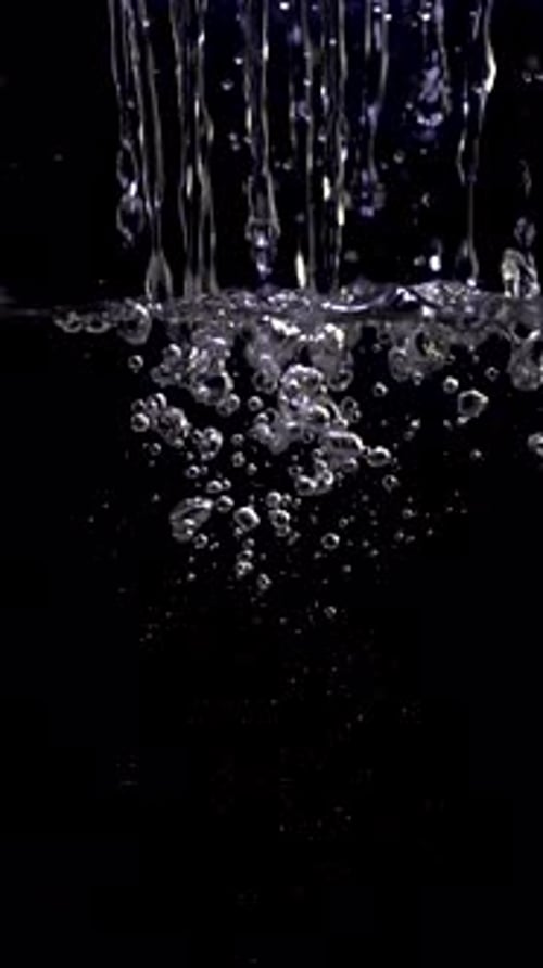 Water Pouring with Splashes and Bubbles on Black