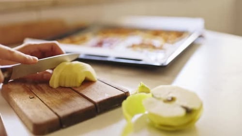 Woman Slicing Apples on Wooden Cutting Board in Kitchen