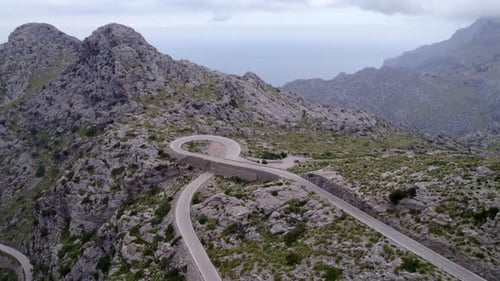 Luftaufnahme einer kurvenreichen Straße durch einen felsigen Gebirgspass, Spanien.