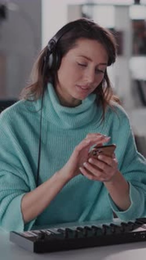 Woman Using Smartphone With Keyboard and Headphones