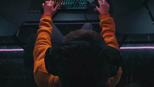 Young Gamer in an ESports Club Sits on Gaming Chair By Monitor Playing Shooter