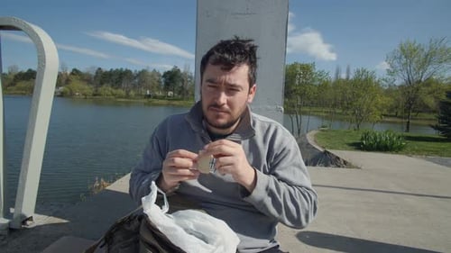 Young Man Eating Sandwich Outside on Sunny Day