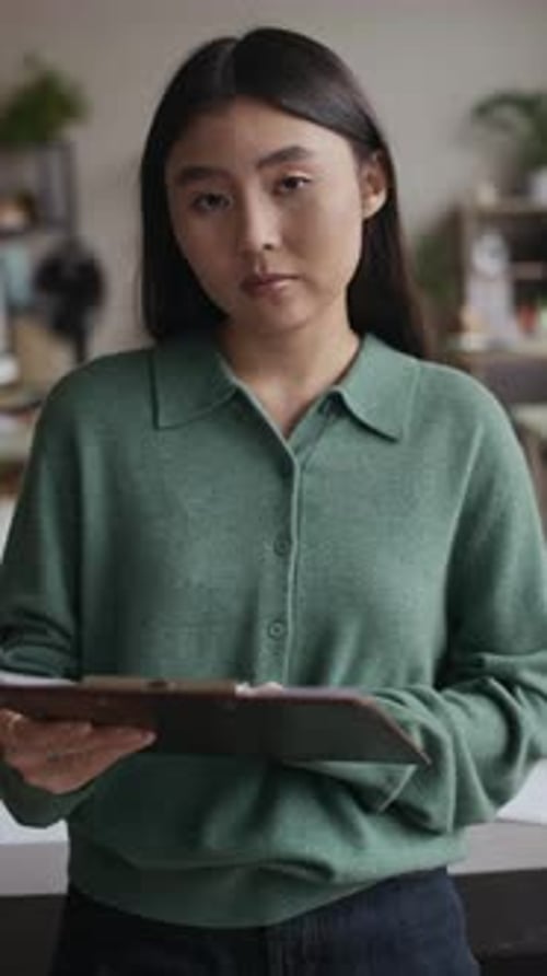 Asian Female Manager Looking at Camera with Folder of Documents