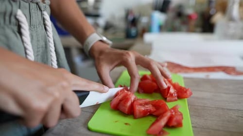 Chef tranchant des tomates fraîches sur une planche à découper verte dans une cuisine lumineuse pour une cuisine gastronomique