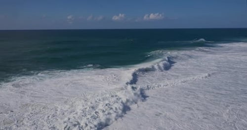 Dynamic Ocean Waves Crashing with White Foam Under a Clear Blue Sky