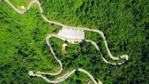 Blick von oben über Autos, die auf einer kurvenreichen Straße im Berg fahren