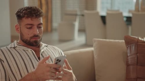 Man Using Smartphone Sitting on Couch Indoors