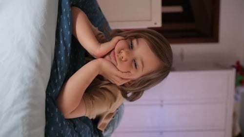 Child Smiling Lying in Bed Looking at Camera