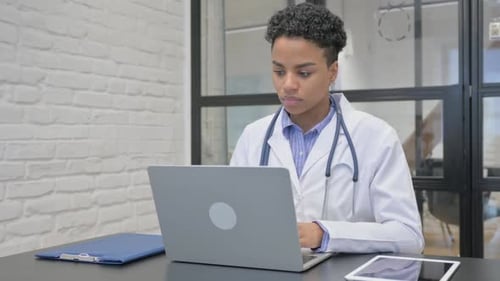 African Female Doctor Working on Laptop in Office
