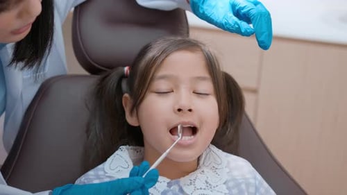 A little cute girl having teeth examined by dentist in dental clinic