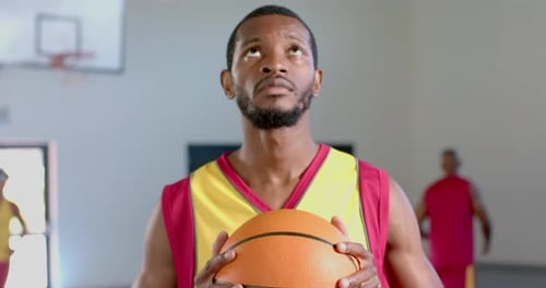 African American man holds a basketball in a gym