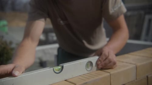 Construction Worker Uses Level to Check Brickwork