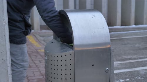 Close up of homeless man takes bottle out for bin to earn some money and help to recycle