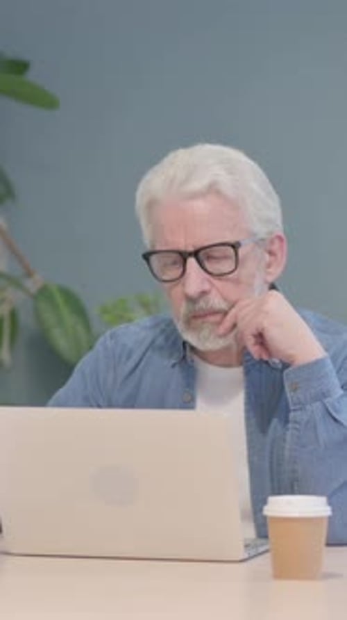 Senior Man Working on Laptop with Coffee Cup