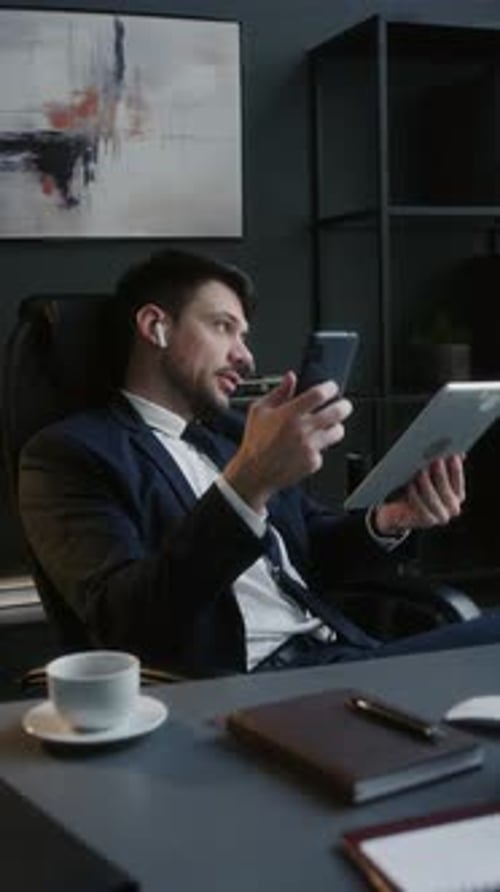 CEO Using Digital Tablet during Phone Conversation in Office
