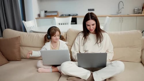 Woman and Child Use Laptops on Couch