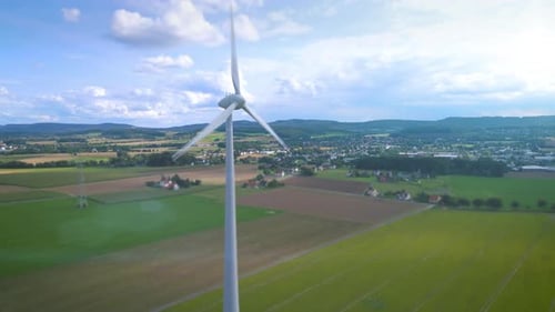 Wind turbine with digital display of green, clean energy production in sunny landscape with agricult