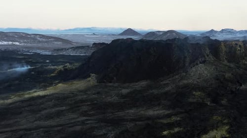 Black basalt solidified lava flow on slope of volcano with yellow mineral surface