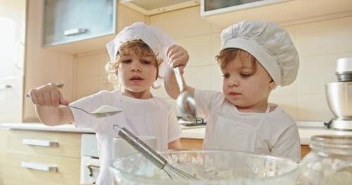 Kinder von angehenden Bäckern messen und fügen Mehl zum Backen in Zeitlupe hinzu