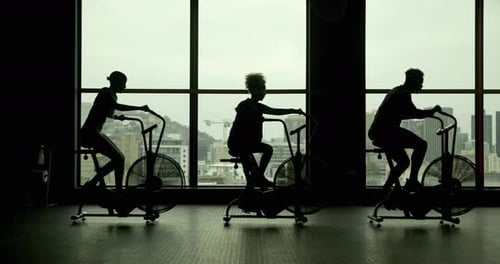 People, bicycle machine and fitness in gym for exercise, commitment and silhouette in sports club