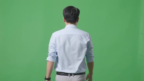 Vista trasera del hombre de negocios asiático caminando sobre fondo de pantalla verde en el estudio