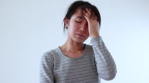 Woman Indoors Massaging Temple in Gray Shirt
