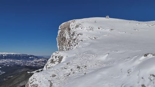 Monts Bucegi enneigés sous un ciel bleu clair, la lumière du soleil projetant des ombres sur les sommets
