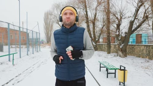 Man Jogging on Snowy Path in Winter