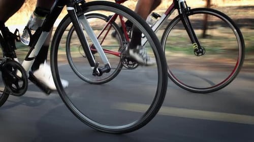 Steadicam Close Up of Two Healthy Men Peddling Fast with Cycling