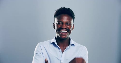 4k video footage of a young man laughing against a grey studio background