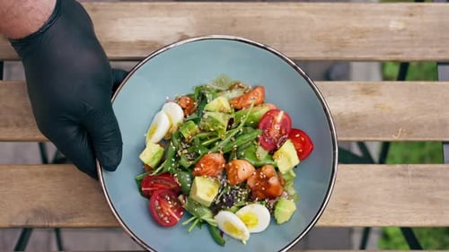 in Restaurant on the Street on a Wooden Table the Chef Pours Oil Into a Warm Salad with Fried