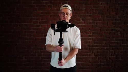 Filmmaker Holds Camera With Steadycam In Front of Wall