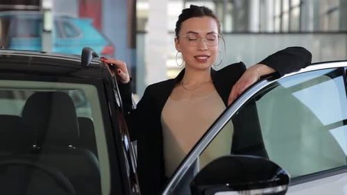 A Young Smiling Business Woman Buys a New Car at a Car Dealership