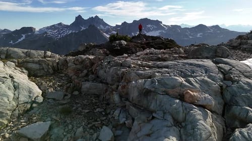 Hiker Standing on Rocky Mountain Summit Overlooking Vast Majestic Landscape in British Columbia