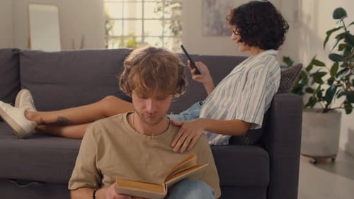 Couple Relaxing at Home Reading and Using Phone