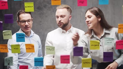 Team of Business People is Doing Brainstorm at a Meeting Using Stickers on the Glass Office Workers