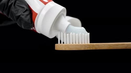 Toothpaste Is Applied to a Wooden Toothbrush, Close-up Isolated on Black Background.