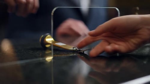 Closeup Receptionist Hand Passing Key to Couple of Tourists at Reception Desk